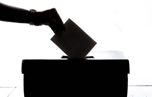 Image d'une main déposant un bulletin de vote dans urne